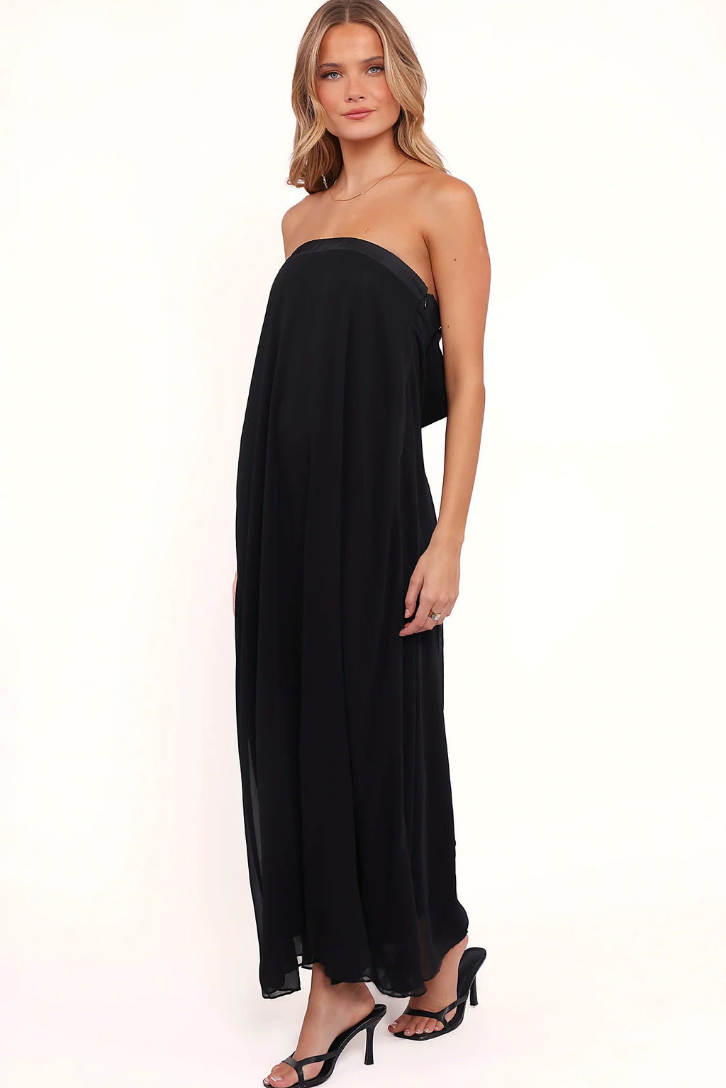 Back view of a black strapless black maxi dress, bow back, showing the fit and drape of the skirt