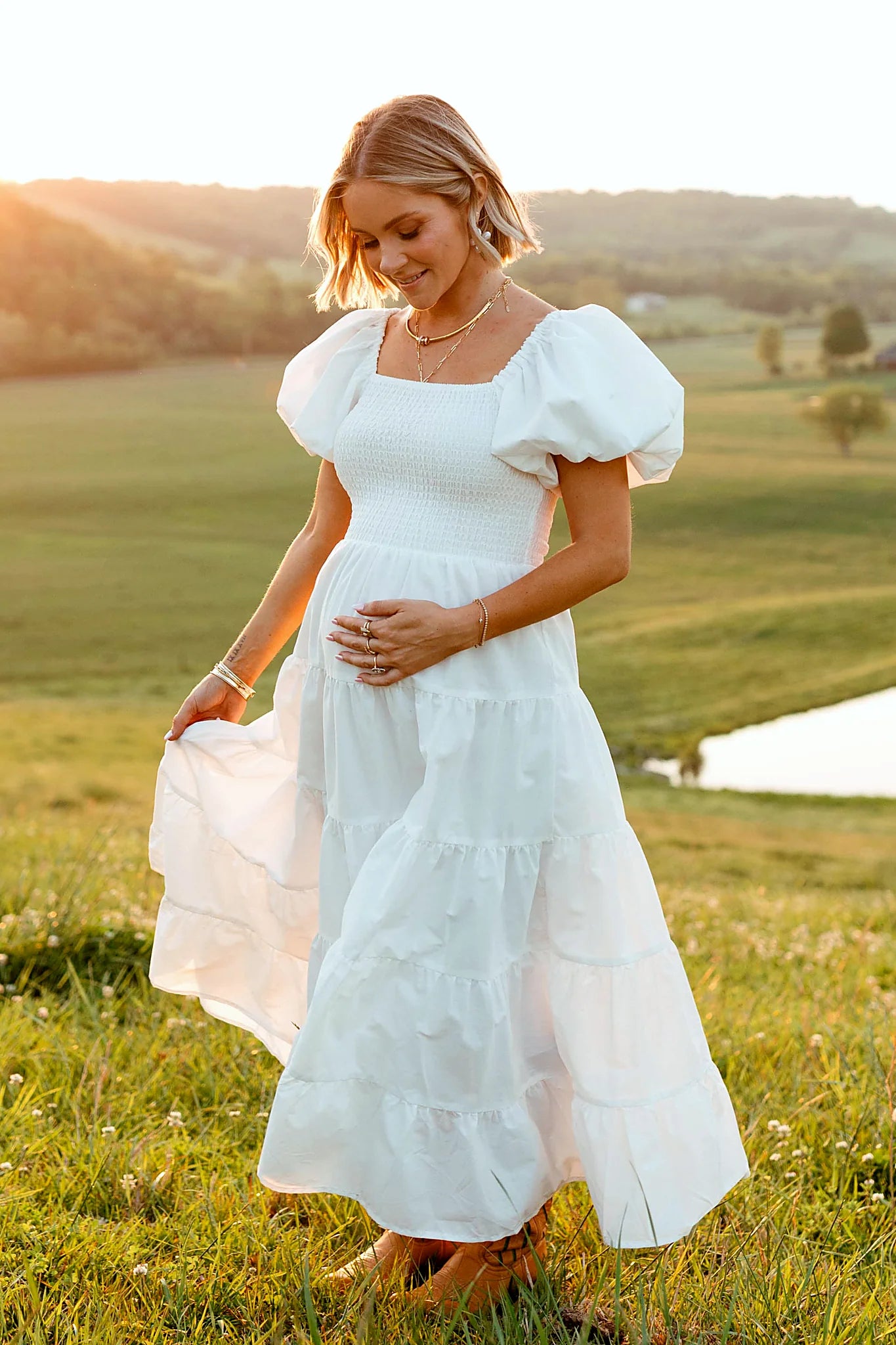 Back view of a white white smocked puff sleeve midi dress, worn by a model against a plain studio backdrop