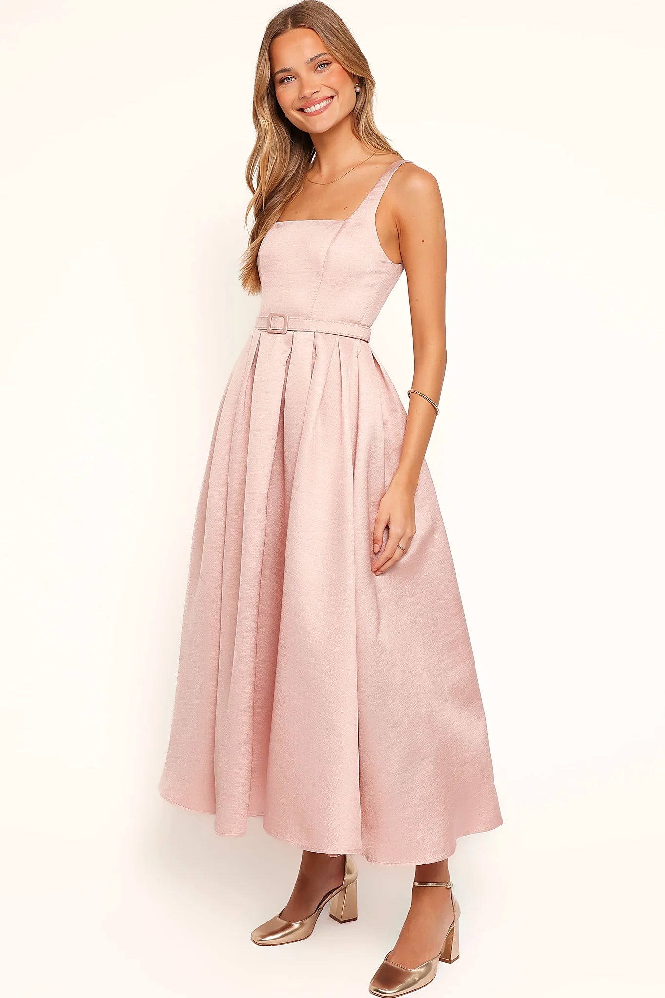 Side view of a pink dusty pink midi dress, tulle underlay, worn by a model against a plain studio backdrop