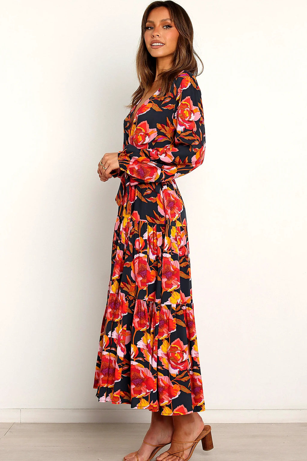 Close-up detail of a navy navy floral tiered overlay maxi dress, worn by a model against a plain studio backdrop