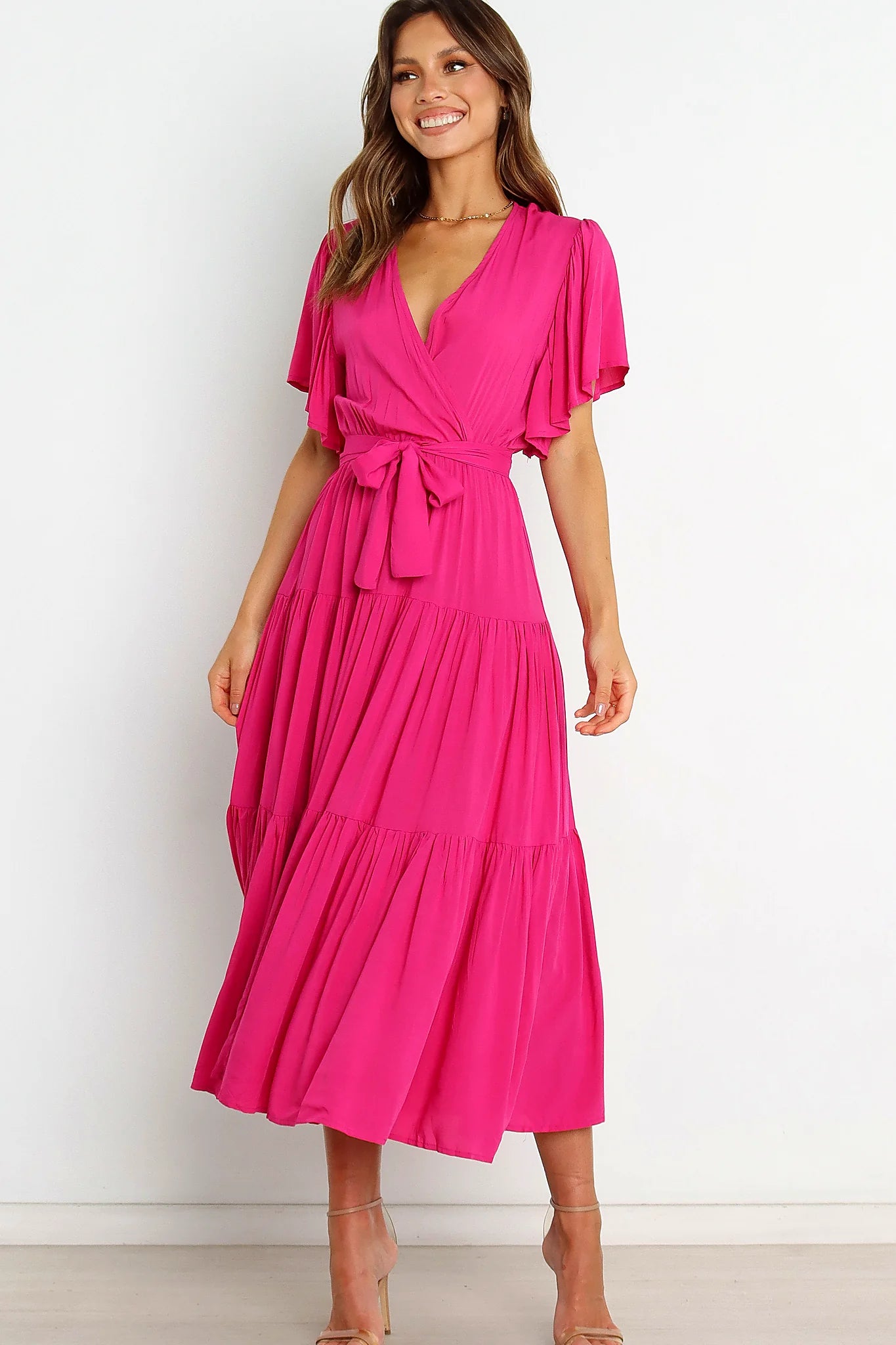 Back view of a pink pink ruffle sleeve tiered midi dress, showing the fabric and hem finish
