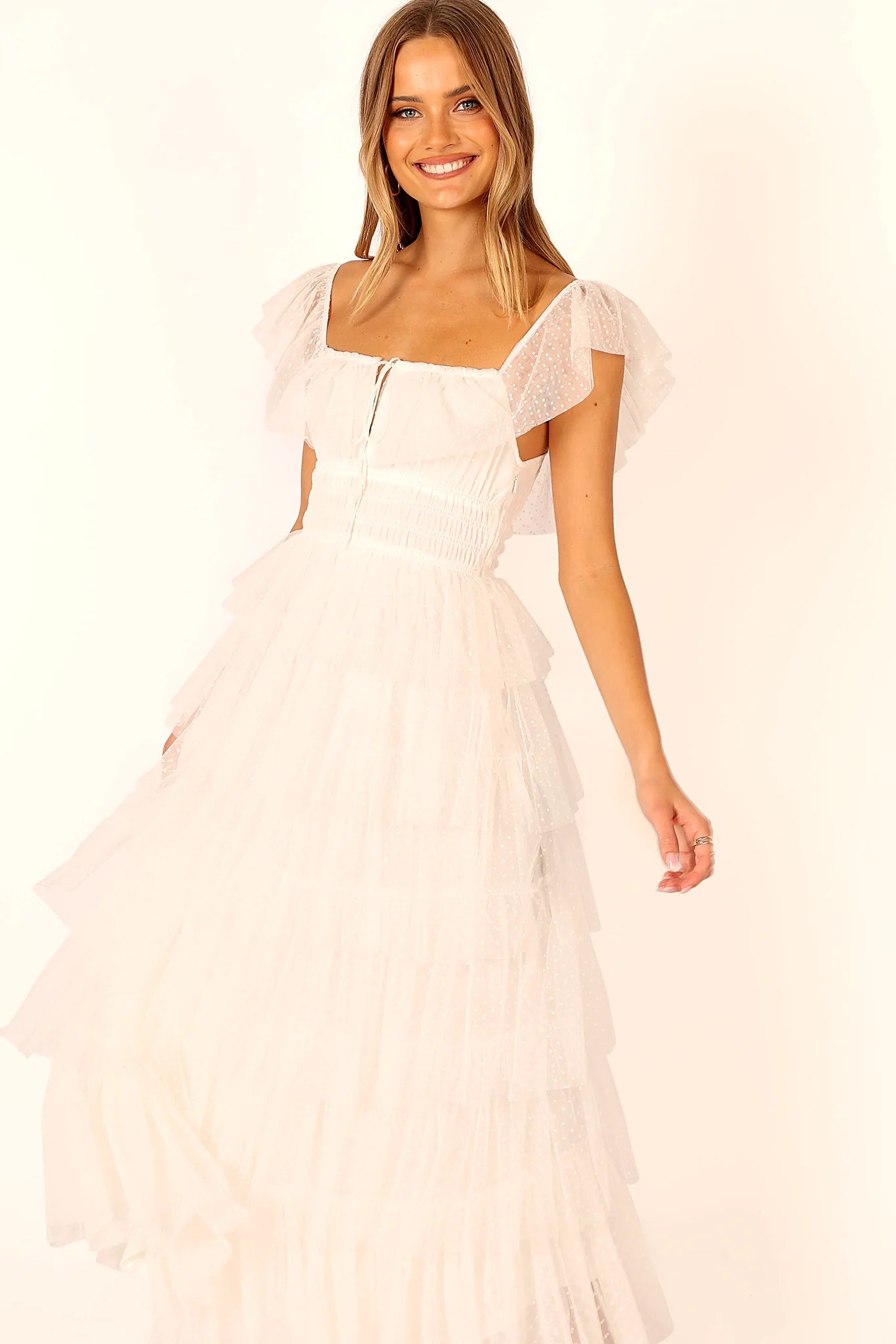 Front view of a white off white tulle maxi dress, worn by a model against a plain studio backdrop