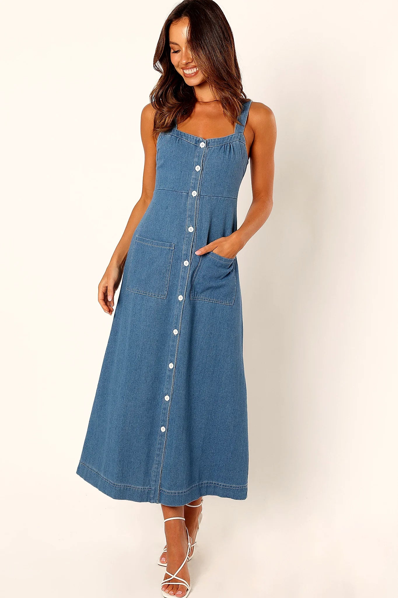 Close-up detail of a denim midi dress, worn by a model against a plain studio backdrop