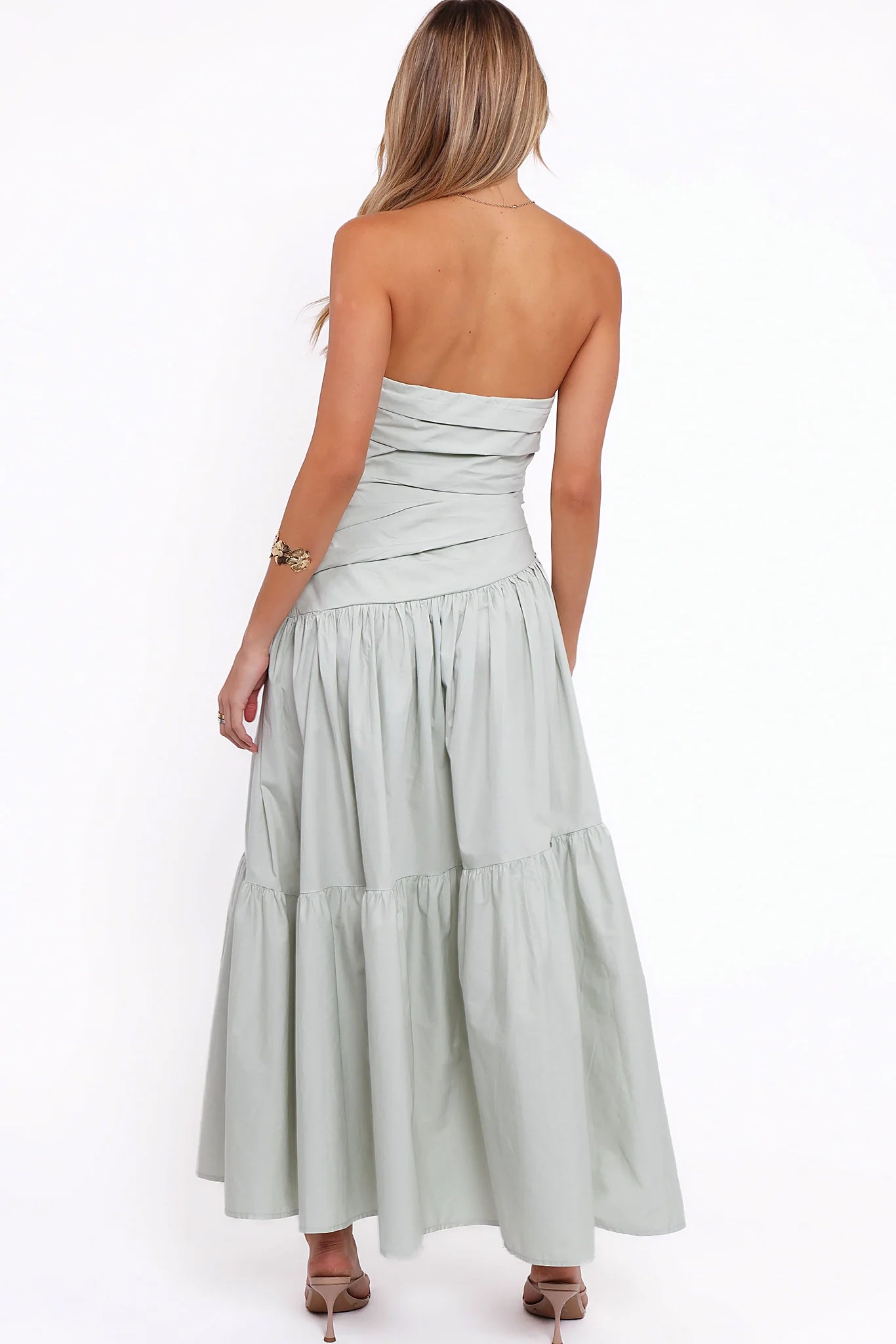 Close-up detail of a mint strapless maxi dress, tiered skirt, worn by a model against a plain studio backdrop