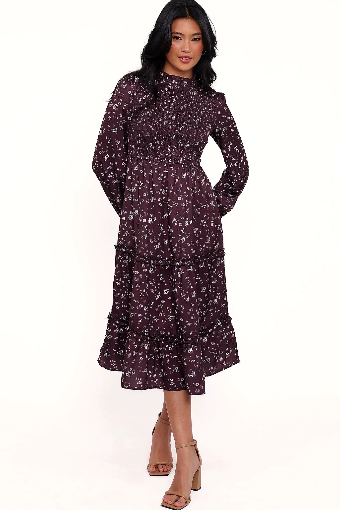 Back view of a plum floral shirred midi dress, frill sleeves, worn by a model against a plain studio backdrop
