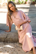 Front view of a feel maxi dress, cut-out back pink satin, worn by a model against a plain studio backdrop