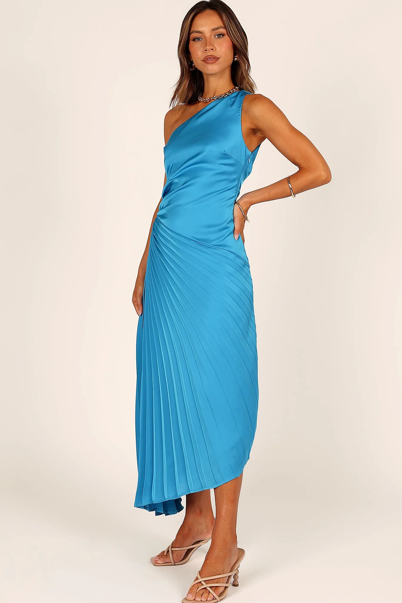 Close-up detail of a blue blue one shoulder pleated midi dress, showing the fabric and hem finish