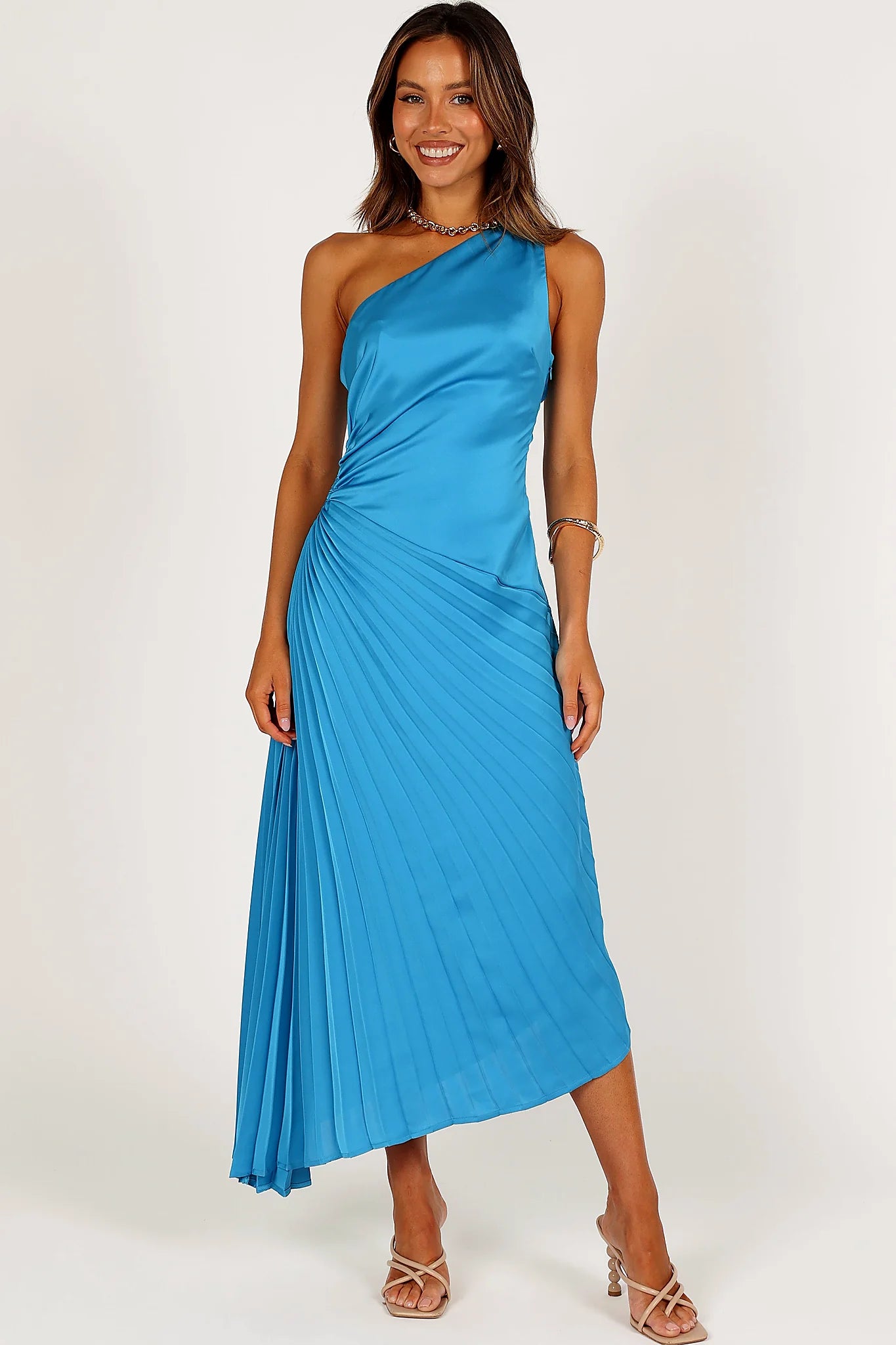 Back view of a blue blue one shoulder pleated midi dress, showing the fit and drape of the skirt
