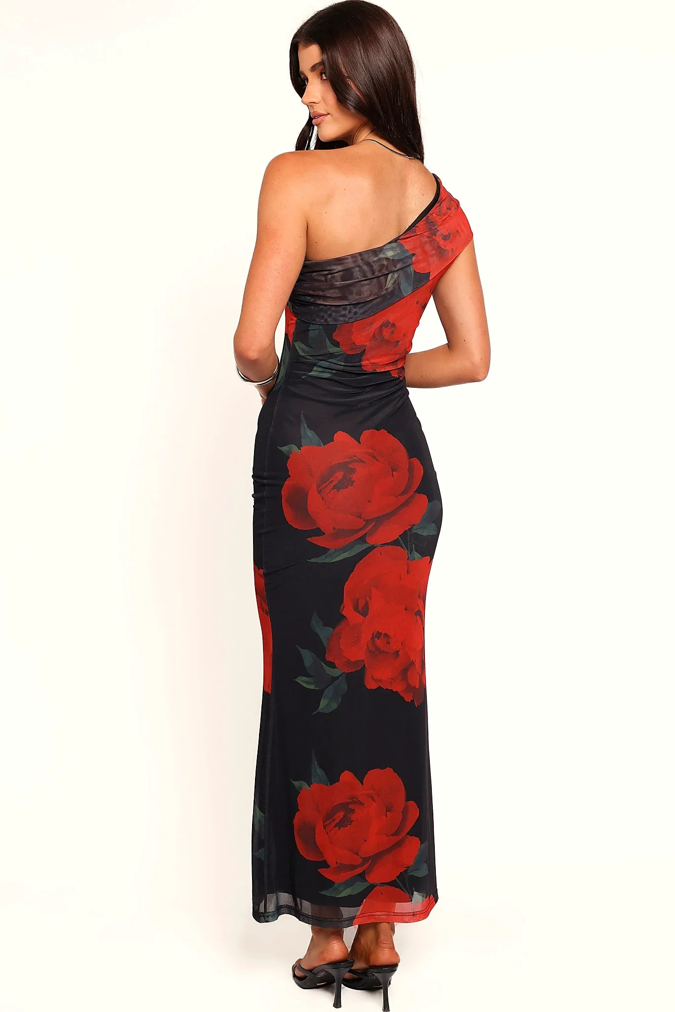 Close-up detail of a black one shoulder black floral maxi dress, worn by a model against a plain studio backdrop