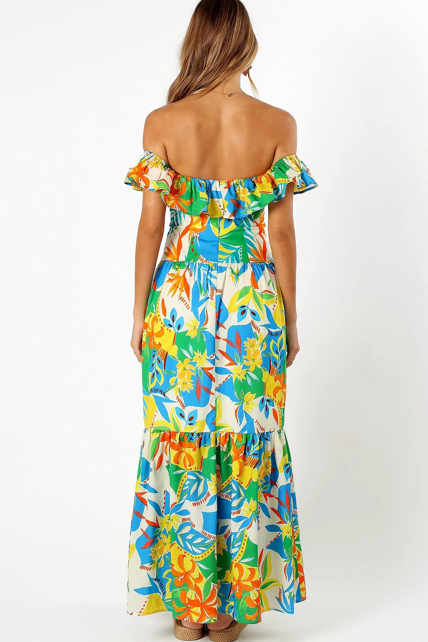 Side view of a malta print maxi dress, ruffle sleeves, worn by a model against a plain studio backdrop
