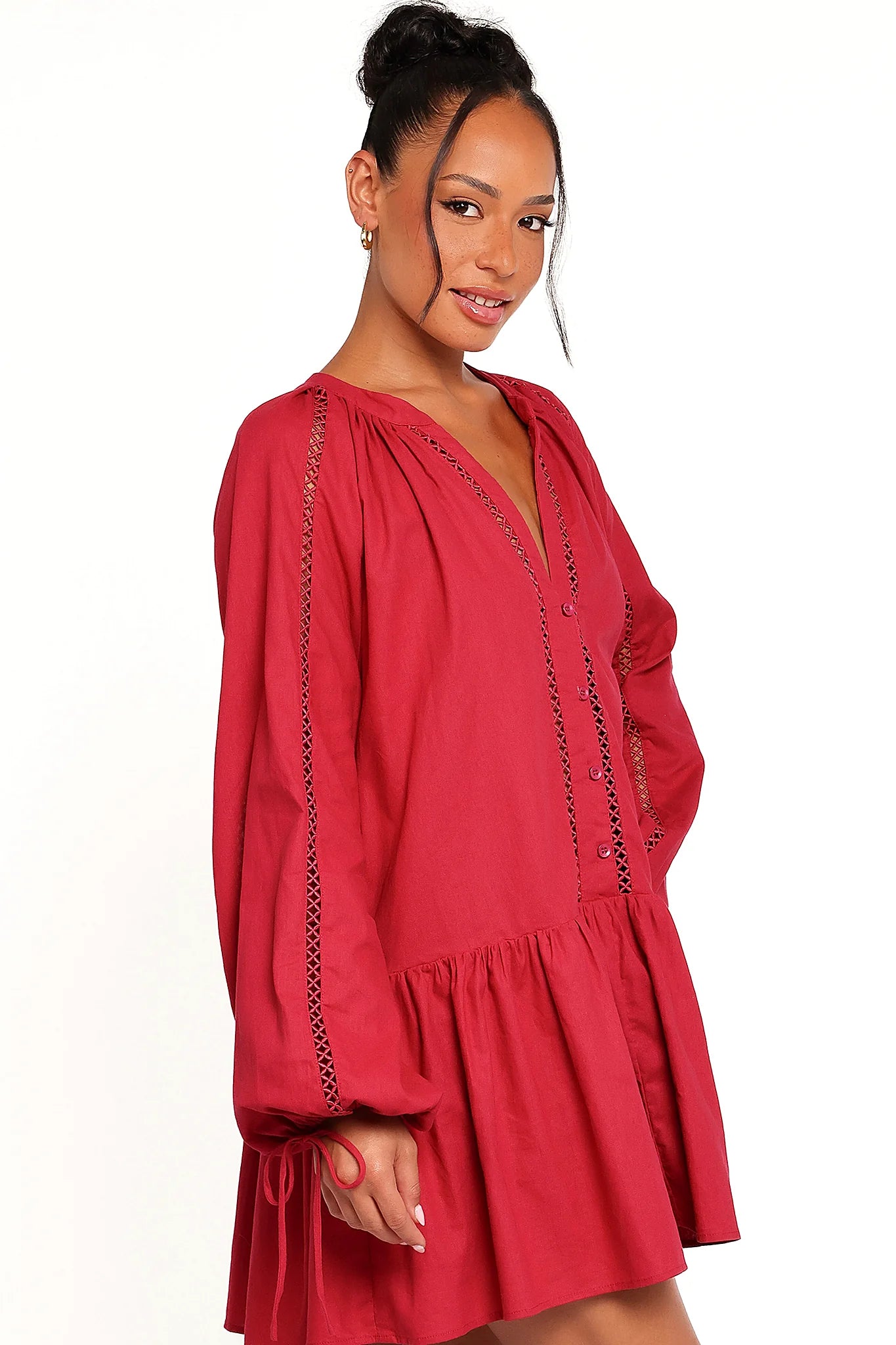 Side view of a red wine mini dress with long sleeves, worn by a model against a plain studio backdrop