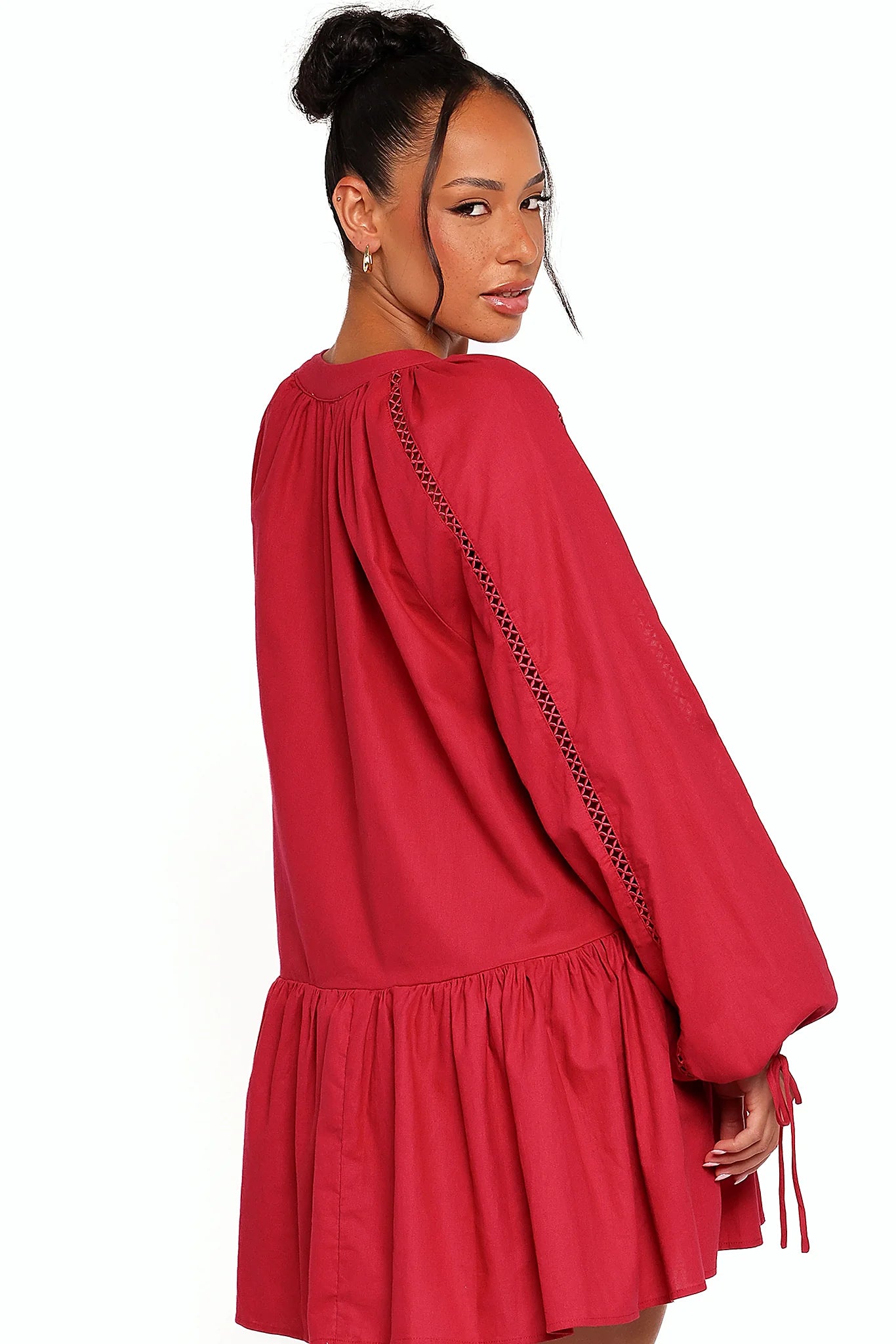 Close-up detail of a red wine mini dress with long sleeves, showing the fit and drape of the skirt
