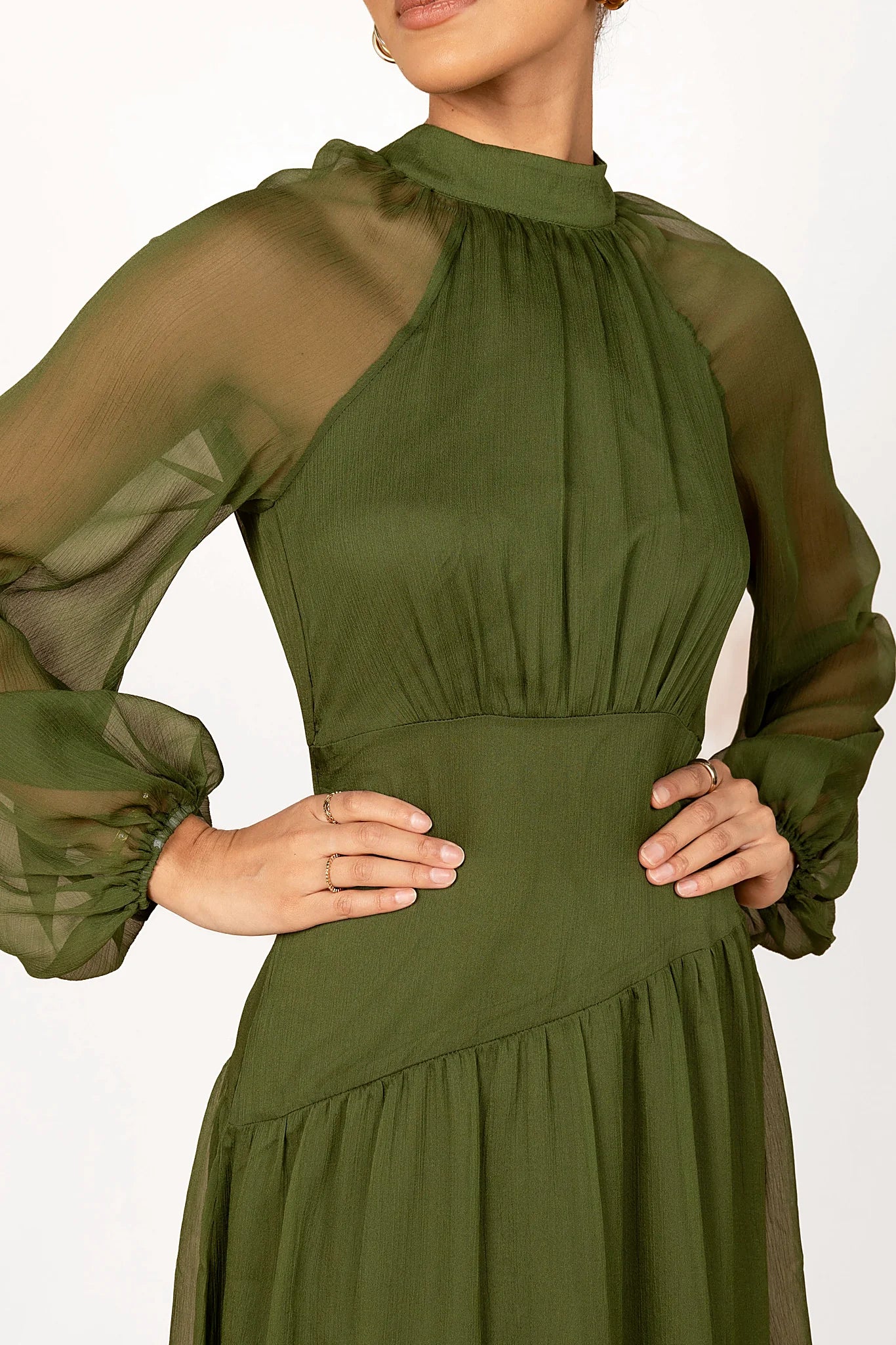 Close-up detail of a olive maxi dress with sheer sleeves, showing the neckline and bodice detail