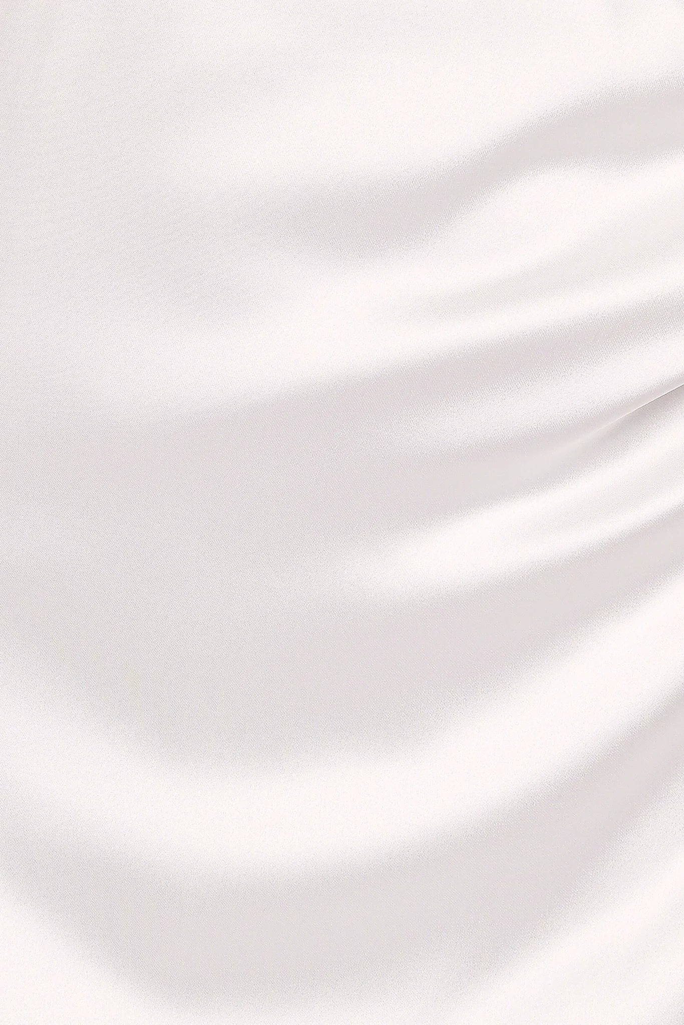 Close-up detail of a white strapless maxi dress, worn by a model against a plain studio backdrop
