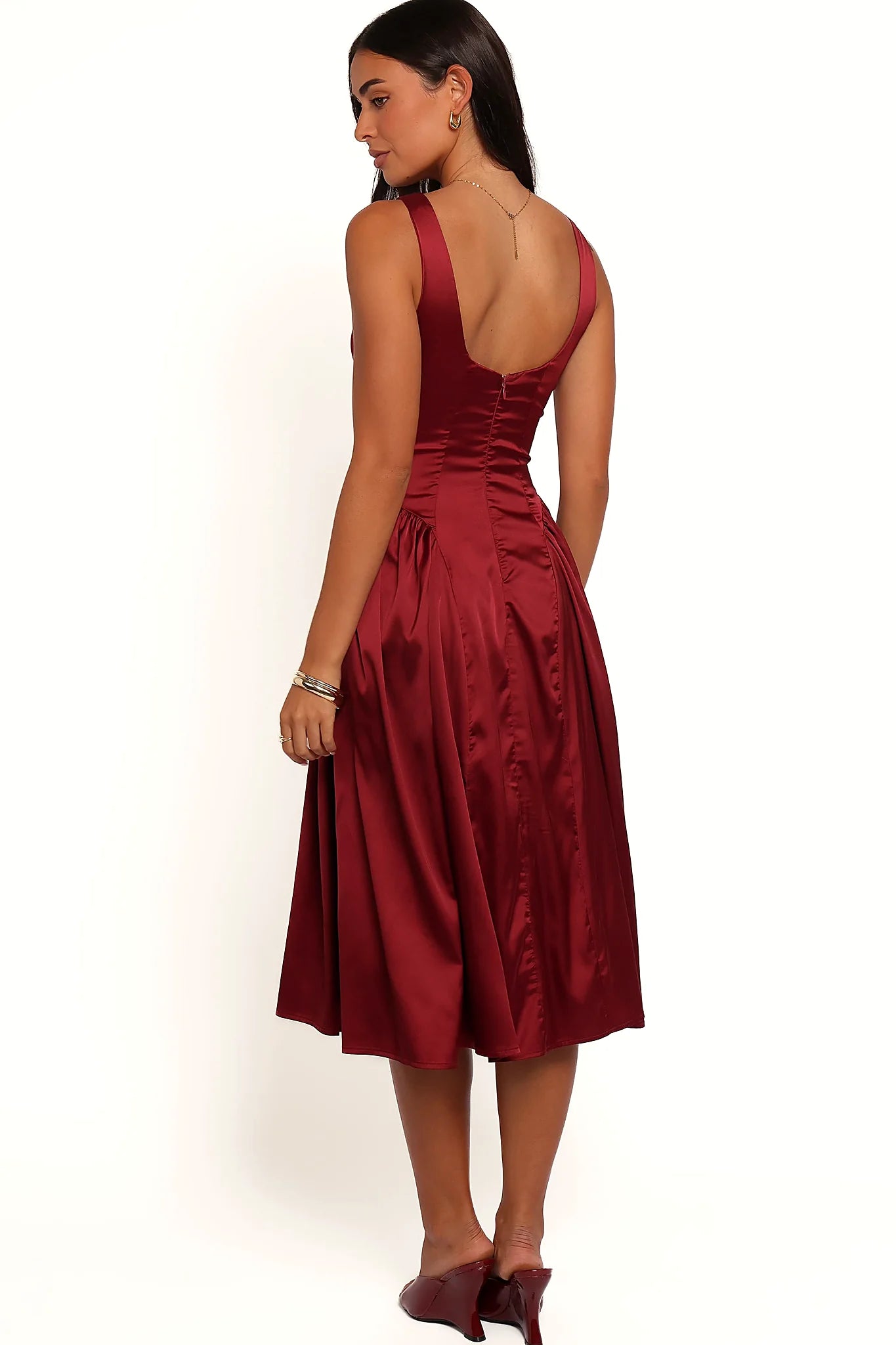 Close-up detail of a red midi dress in deep burgundy, worn by a model against a plain studio backdrop