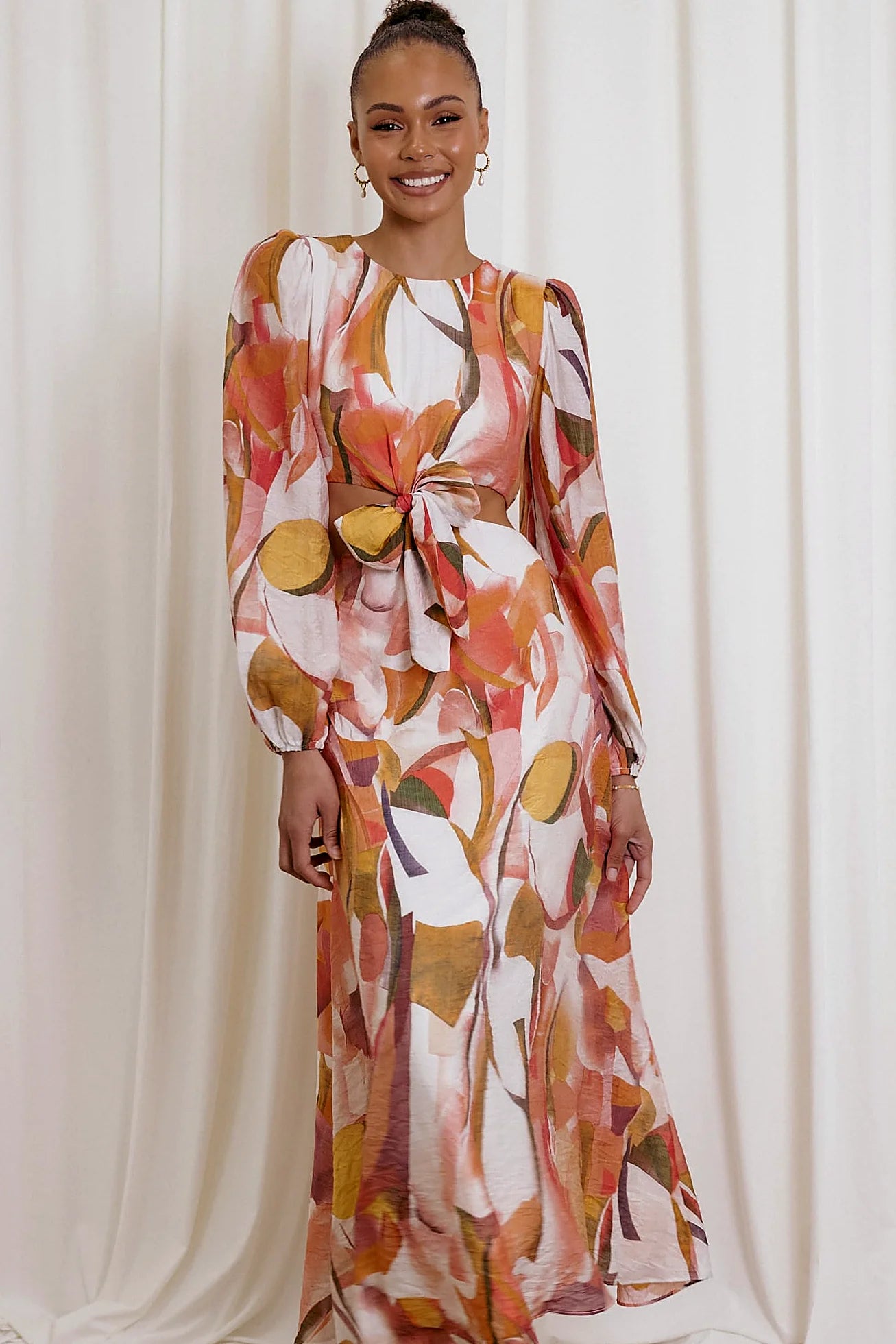 Back view of a pink pink abstract print maxi dress, worn by a model against a plain studio backdrop