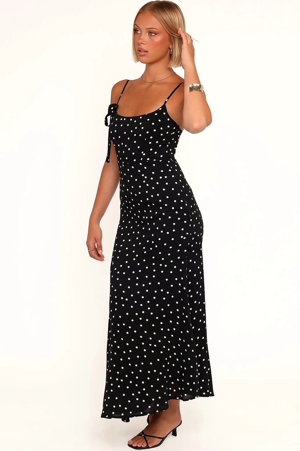 Side view of a black polka dot midi dress, showing the fit and drape of the skirt