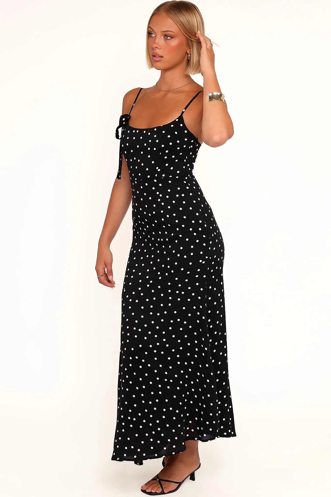 Side view of a black polka dot midi dress, showing the fit and drape of the skirt