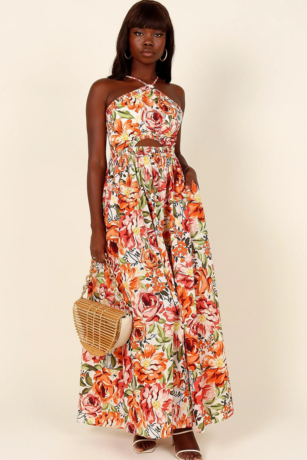 Side view of a orange floral halterneck maxi dress, showing the fabric and hem finish