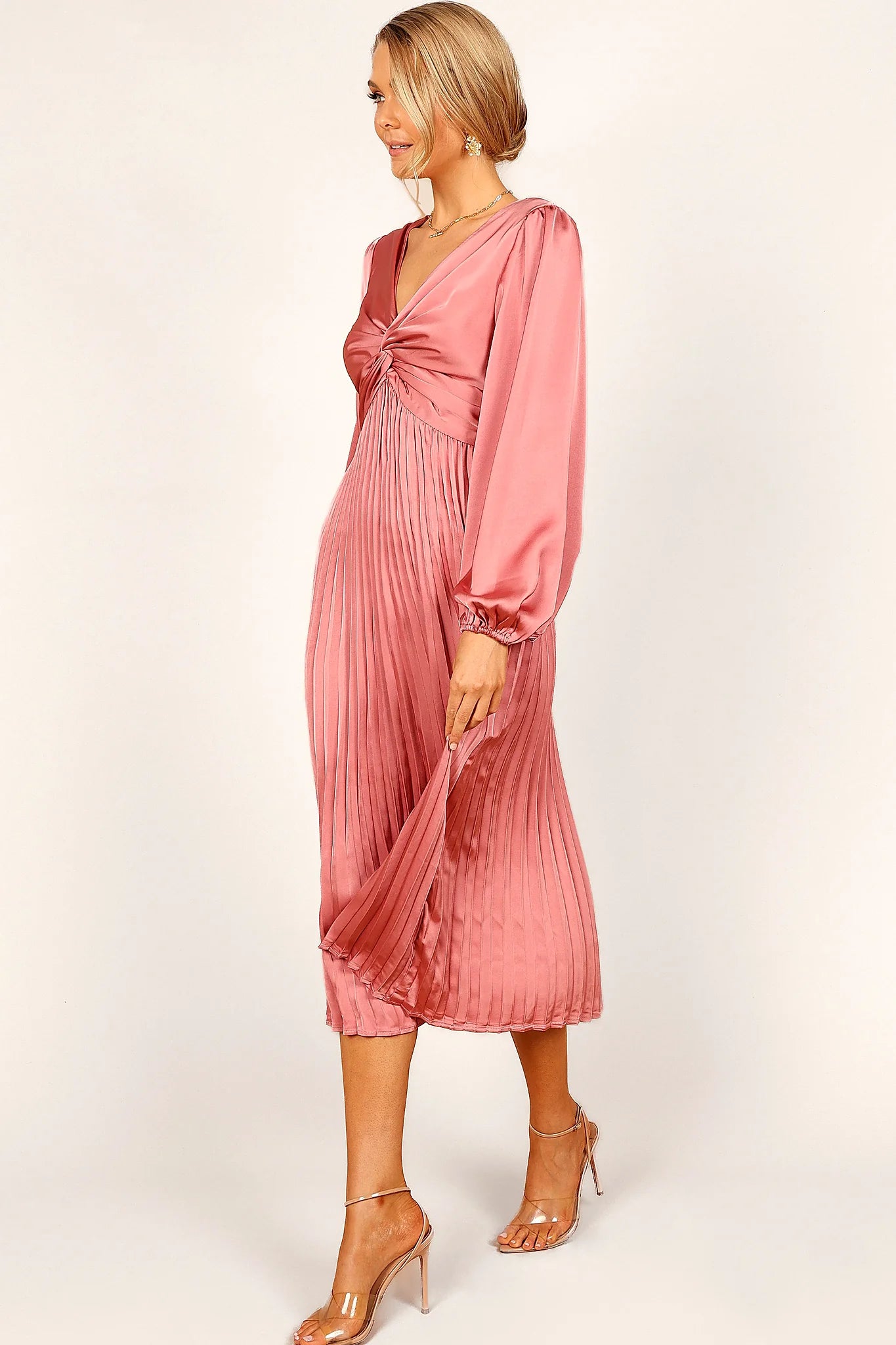 Close-up detail of a pink blush twist front pleated midi dress, showing the fit and drape of the skirt