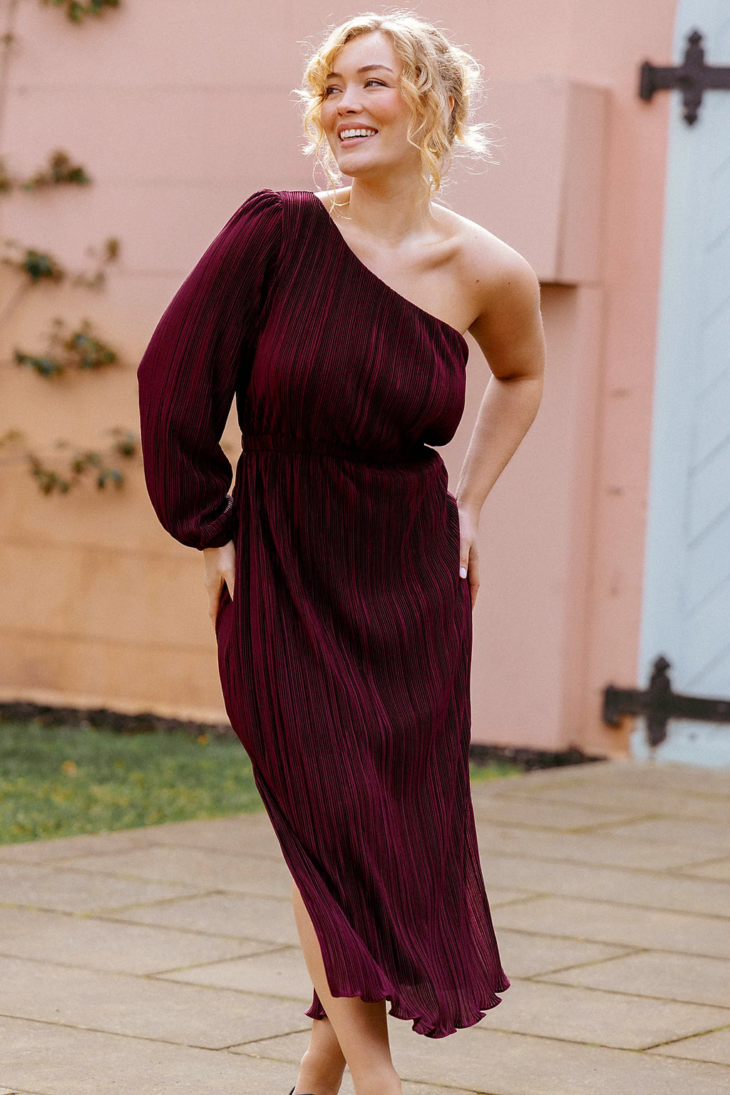 Back view of a red burgundy one shoulder pleated midi dress, showing the fabric and hem finish