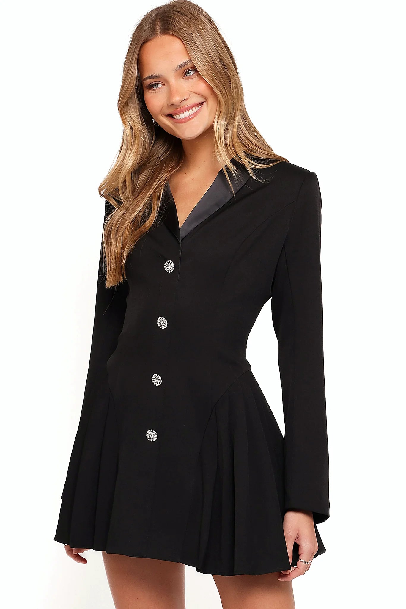 Close-up detail of a black black mini dress, padded shoulders, showing the fabric and hem finish