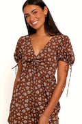 Front view of a brown ditsy floral maxi dress, showing the fabric and hem finish